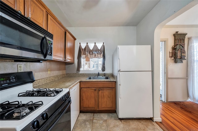 kitchen featuring gas stove, white fridge, sink, and dishwashing machine