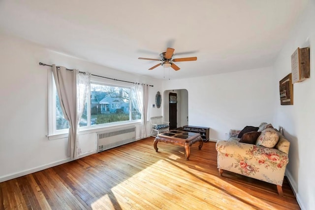 sitting room with hardwood / wood-style floors, radiator heating unit, and ceiling fan