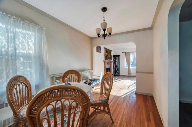 dining area with an inviting chandelier, crown molding, and dark wood-type flooring