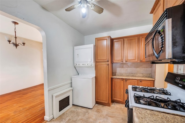 kitchen featuring pendant lighting, light tile patterned floors, ceiling fan, stacked washer / dryer, and range with gas stovetop