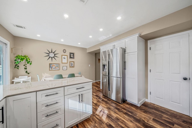 kitchen featuring light stone counters, stainless steel fridge, dark hardwood / wood-style floors, and white cabinets