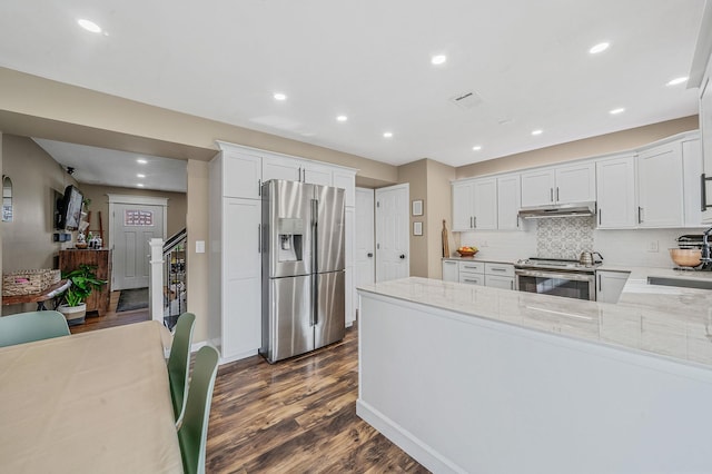 kitchen with stainless steel appliances, dark hardwood / wood-style floors, white cabinets, and light stone counters