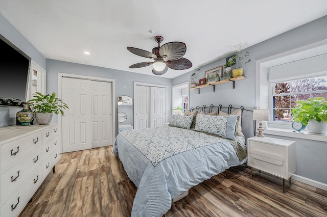 bedroom with multiple closets, ceiling fan, and dark hardwood / wood-style floors