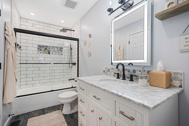 full bathroom with toilet, shower / bath combination with glass door, vanity, hardwood / wood-style floors, and backsplash