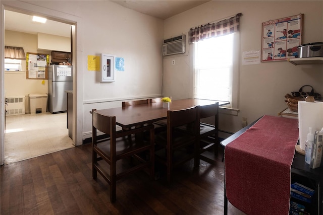 dining space with radiator heating unit, dark hardwood / wood-style floors, and a wall mounted air conditioner