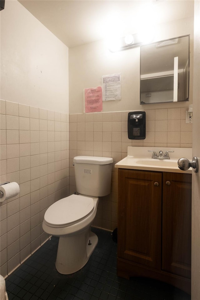 bathroom featuring vanity, toilet, tile patterned flooring, and tile walls