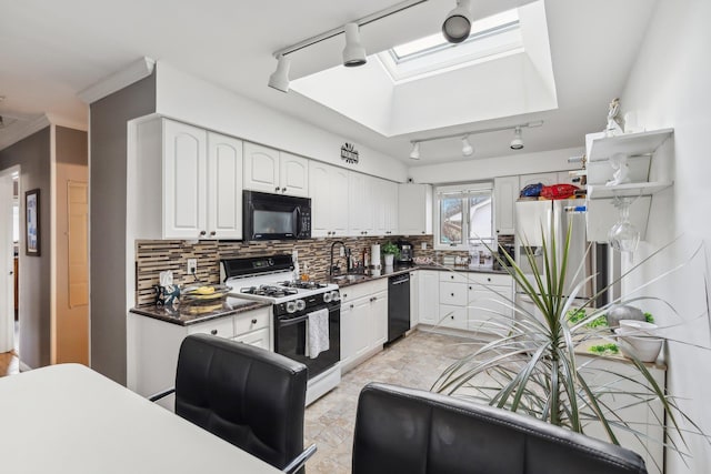 kitchen featuring sink, black appliances, a skylight, white cabinets, and backsplash