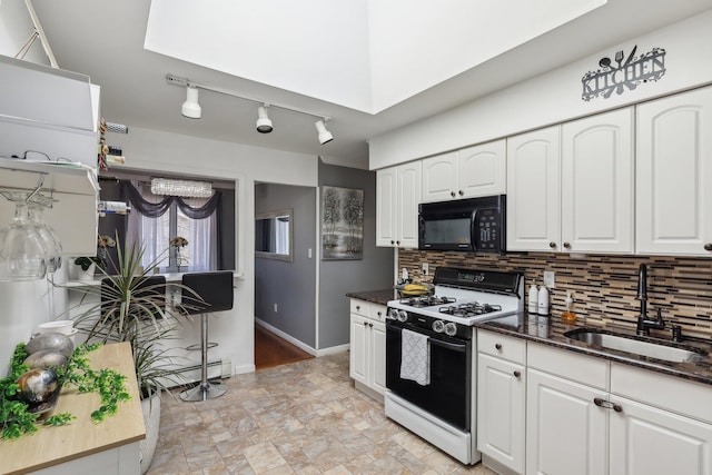 kitchen with sink, white cabinets, dark stone counters, decorative backsplash, and gas range