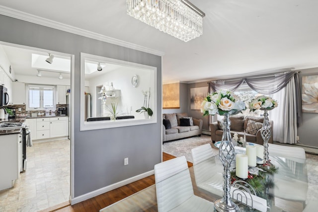 dining room featuring a baseboard radiator, ornamental molding, a notable chandelier, track lighting, and light wood-type flooring