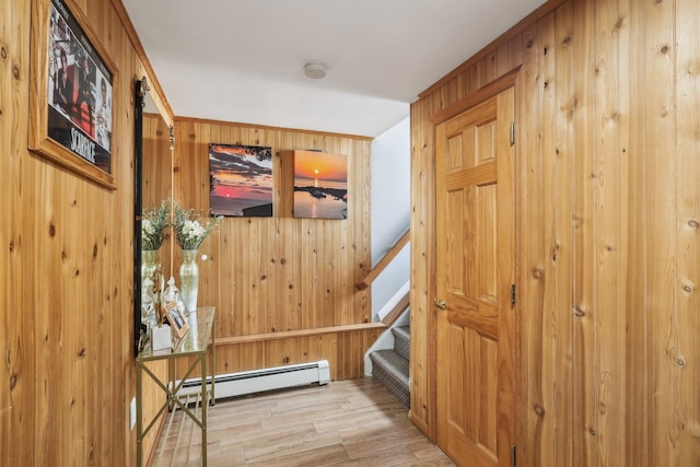 hall featuring a baseboard radiator, light wood-type flooring, and wood walls