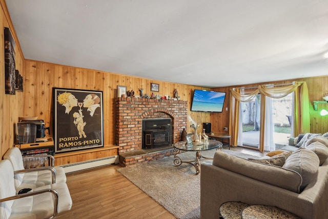 living room featuring wood-type flooring, a baseboard heating unit, a wood stove, and wood walls