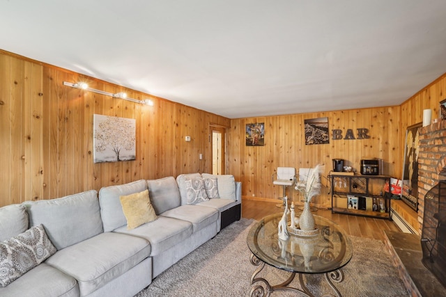 living room featuring a baseboard heating unit, hardwood / wood-style flooring, and a brick fireplace