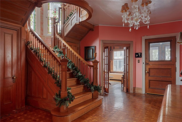 foyer entrance with stairs, ornamental molding, radiator heating unit, and a notable chandelier