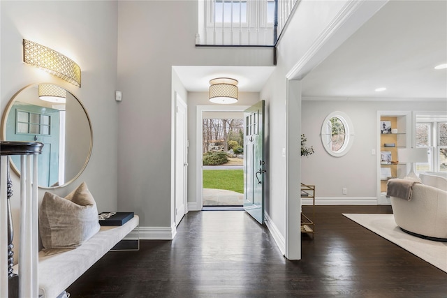 foyer entrance with ornamental molding, dark wood-type flooring, a high ceiling, and baseboards