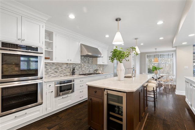 kitchen featuring wine cooler, open shelves, stainless steel appliances, white cabinets, and wall chimney exhaust hood