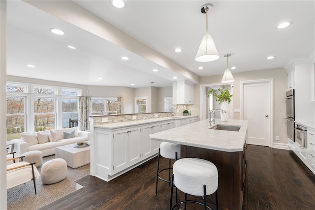 kitchen with a peninsula, tasteful backsplash, dark wood-type flooring, and a sink