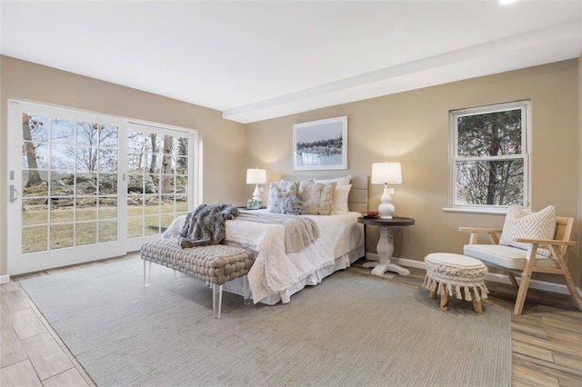 bedroom with multiple windows, baseboards, and wood finished floors