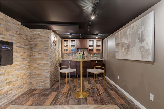 bar with wood tiled floor, baseboards, tasteful backsplash, and indoor wet bar