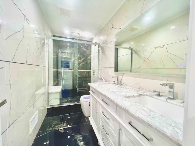 bathroom with tile walls, an enclosed shower, vanity, and toilet