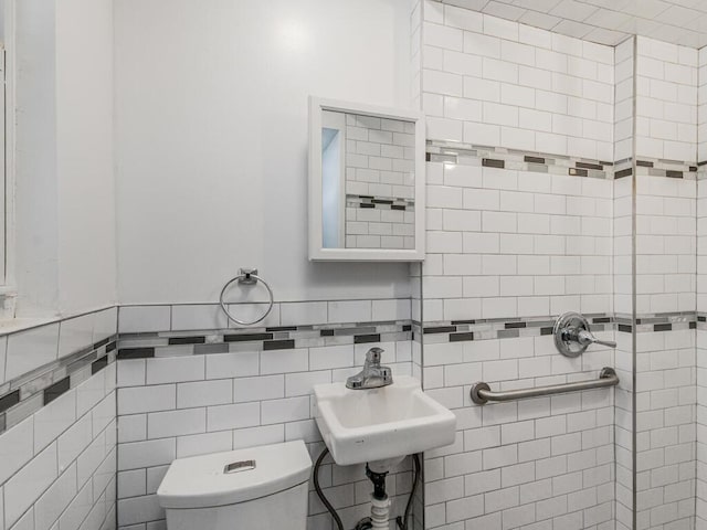 bathroom featuring toilet, sink, and tile walls