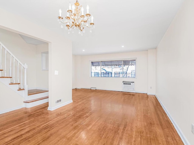 unfurnished living room featuring hardwood / wood-style floors and a wall unit AC