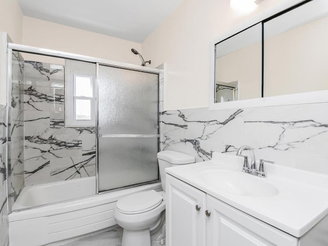 full bathroom with vanity, tile walls, toilet, and combined bath / shower with glass door