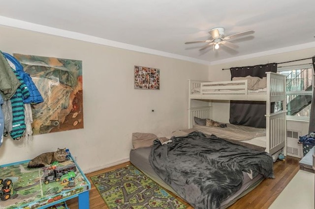 bedroom featuring dark wood-type flooring, ceiling fan, ornamental molding, and radiator