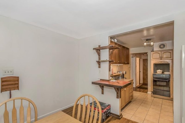 kitchen with light tile patterned floors, oven, and a kitchen bar