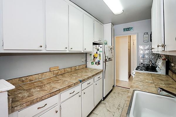 kitchen featuring white refrigerator, range, sink, and white cabinets