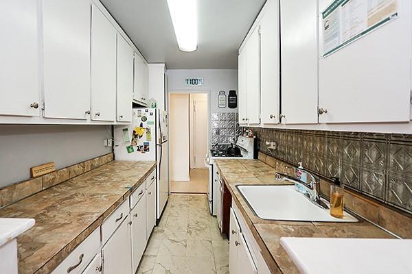 kitchen with sink, backsplash, white cabinets, and white appliances