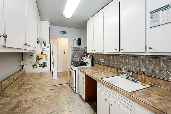 kitchen featuring sink, backsplash, white cabinets, and white appliances