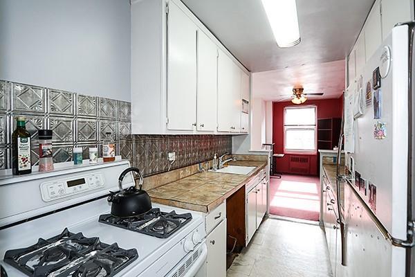 kitchen featuring sink, white appliances, ceiling fan, backsplash, and white cabinets