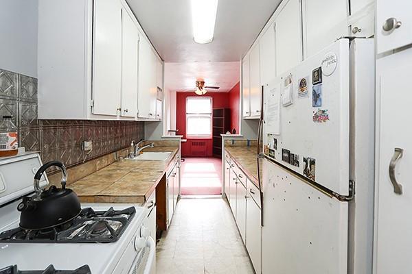 kitchen with tasteful backsplash, white appliances, sink, and white cabinets