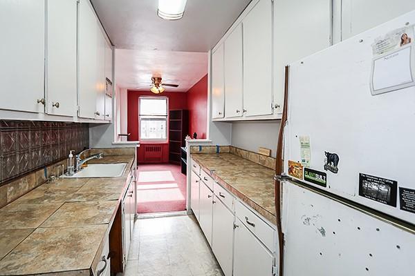 kitchen with white cabinetry, sink, ceiling fan, and white refrigerator