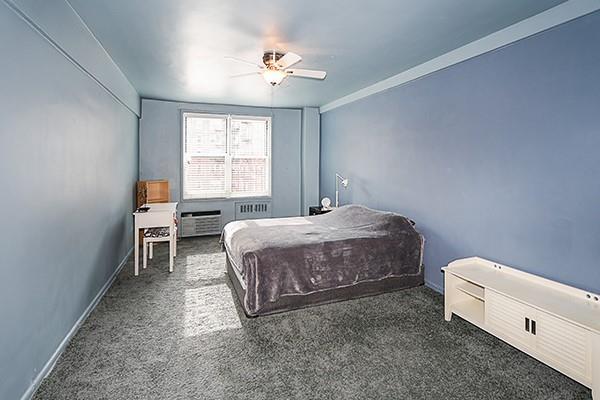 carpeted bedroom with ceiling fan and a baseboard radiator