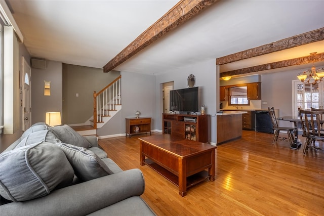 living room with an inviting chandelier, beam ceiling, and light hardwood / wood-style flooring