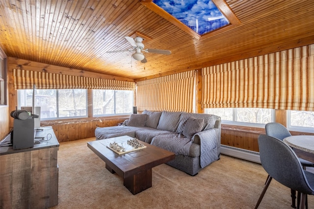 living room with wood walls, wooden ceiling, a baseboard radiator, carpet floors, and ceiling fan