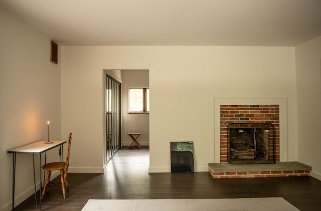 living room with dark hardwood / wood-style flooring and a brick fireplace