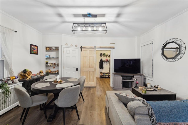 dining room with crown molding, wood-type flooring, and a barn door