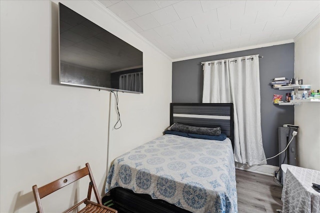 bedroom with ornamental molding and hardwood / wood-style floors