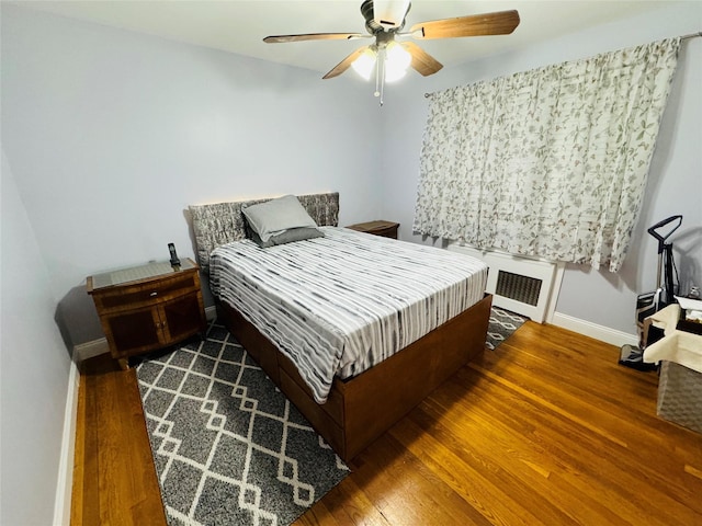 bedroom with ceiling fan, dark hardwood / wood-style floors, and radiator