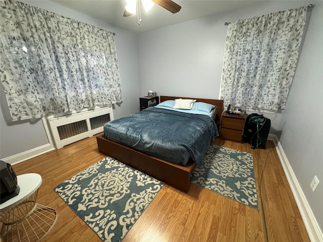 bedroom featuring ceiling fan, radiator, and hardwood / wood-style floors