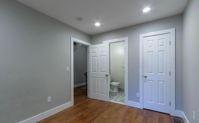 unfurnished bedroom featuring dark wood-type flooring and ensuite bathroom