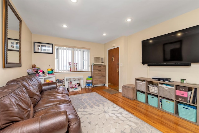 living room with hardwood / wood-style flooring, radiator heating unit, and a wall unit AC