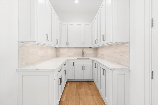 kitchen featuring tasteful backsplash, sink, light hardwood / wood-style floors, and white cabinets