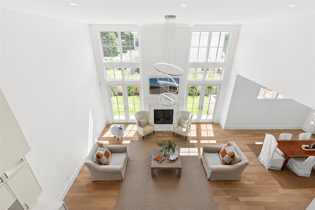 living room with a healthy amount of sunlight, a large fireplace, light wood-type flooring, and french doors