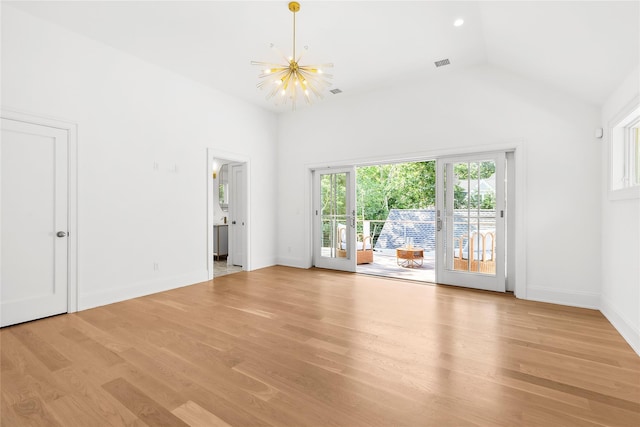 unfurnished living room featuring plenty of natural light, a chandelier, high vaulted ceiling, and light wood-type flooring