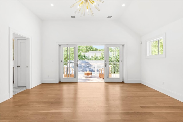 empty room featuring french doors, vaulted ceiling, a chandelier, and light hardwood / wood-style floors