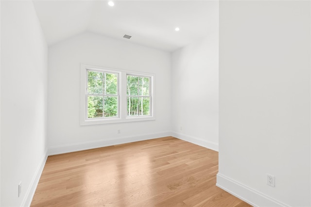 spare room with lofted ceiling and light hardwood / wood-style floors