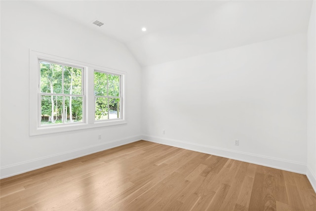 spare room featuring lofted ceiling and light hardwood / wood-style flooring